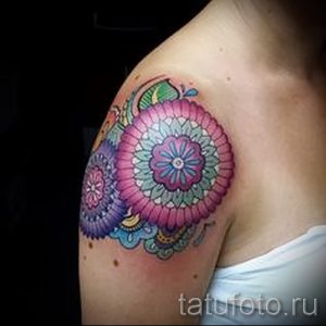 Фото татуировки: две яркие мандалы на плече девушки, разноцветный рисунок, детализированный узор, вид спереди.