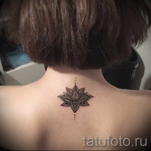 Фото тату: маленькая татуировка мандалы на затылке девушки. Черно-белая татуировка с тонкими линиями и детализированным узором.