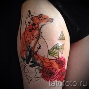 Фото тату лисы на плече, выполненное в технике акварели с добавлением геометрических фигур и цветов. Рисунок татуировки сочетает в себе нежные оттенки красного и зеленого.