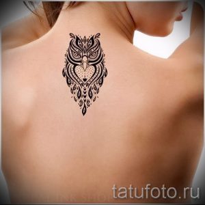 Фото тату: татуировка совы на затылке девушки. Черно-белая татуировка с геометрическими узорами и тонкими линиями.