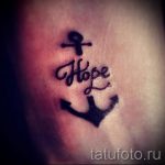 Фото тату: маленькая татуировка на коже, изображающая якорь и надпись "Hope". Морская тематика, минимализм, надежда.