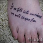 Фото тату с надписью "If we fall into ourselves we will become free" на стопе, выполненное черными чернилами. Рисунок выполнен каллиграфическим шрифтом. Эскиз татуировки выглядит вдохновляюще и мотивирующе.