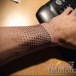 Фото тату: татуировка, выполненная в технике дотворк, представляет собой узор из точек на предплечье. Минималистичный дизайн, геометрический рисунок.