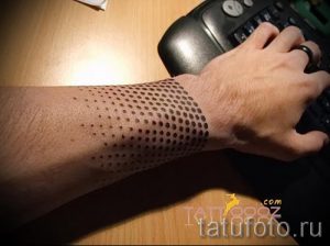Фото тату: татуировка, выполненная в технике дотворк, представляет собой узор из точек на предплечье. Минималистичный дизайн, геометрический рисунок.