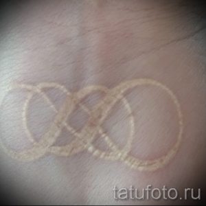 Фото тату: Светлый эскиз татуировки в виде символа бесконечности, нанесенный на руку. Рисунок выглядит как легкий набросок.