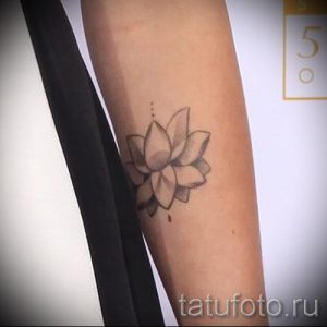 Фото тату: небольшая, серая татуировка лотоса на предплечье. Минималистичный и элегантный рисунок татуировки.
