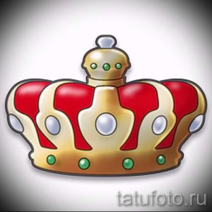 Фото татуировки в виде красной короны с золотой окантовкой и зелеными камнями. Яркий и привлекательный дизайн.