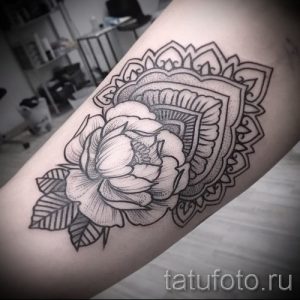 Фото тату пиона, заключенного в сложную мандалу, выполненную в технике дотворк. Расположена на предплечье, черно-белая.