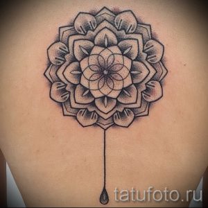 Фото татуировки мандалы на спине. Чёрно-серый рисунок с эффектом стекающей капли, выполненный в технике дотворк.