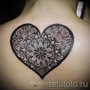 Фото татуировки мандалы, выполненной в форме сердца на спине. Чёрно-белый рисунок с высокой детализацией и сложными узорами.