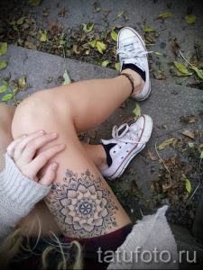 Фото тату: детальная мандала в стиле дотворк на женском бедре. Черно-белый рисунок татуировки с тонкими линиями и геометрическими узорами.