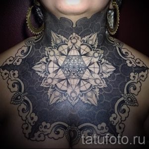 Фото тату мандалы на груди. Черно-серая татуировка с геометрическими узорами и тонкими линиями. Детализированный рисунок татуировки.