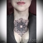 Фото тату: большая черно-белая мандала, выполненная в технике дотворк, украшает шею и верхнюю часть груди. Детализированный рисунок с использованием точек разного размера.