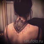 Фото тату: черная мандала с красными точками на спине девушки. Детализированный рисунок татуировки с геометрическими узорами и тонкими линиями.