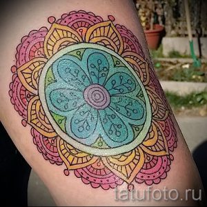 Фото тату мандалы на ноге, выполненной в нежных пастельных тонах. Детализированный рисунок татуировки с плавными переходами и сложными узорами.