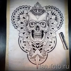 Черно-белый эскиз татуировки черепа, заключенного в мандалу. Символический рисунок, сочетающий в себе темы жизни, смерти и духовности.