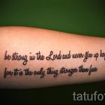 Фото тату: надпись "be strong in the Lord and never give up hope, for it is the only thing stronger than fear" выполнена черным цветом на предплечье.