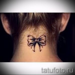 Фото тату черного банта на задней части шеи. Простой и элегантный рисунок татуировки, выполненный в технике контурной графики.