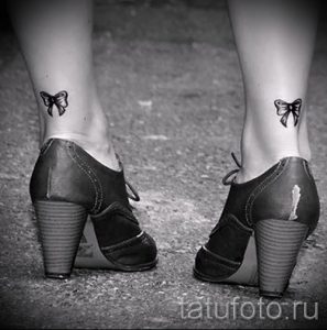 Фото тату двух небольших черных бантиков, расположенных на лодыжках. Изящный и минималистичный дизайн.