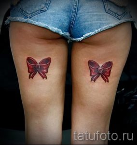 Фото парных татуировок: два красных бантика с сердечком, расположенных на бедрах. Идеально для сестер или подруг.