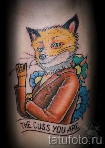 Фото татуировки лисы в куртке и с сигаретой, с надписью "The cuss you are". Стиль олдскул, яркие цвета.