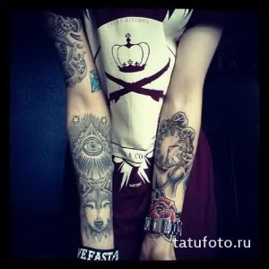Фото тату на руке: Комплексная татуировка в виде рукава с изображением Всевидящего ока, волка, часов и других символов. Детализированный и многослойный рисунок татуировки.