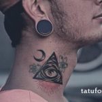 Фото тату на шее: глаз в треугольнике, украшенный луной, звездами и лучами света. Черно-белый рисунок татуировки с мистическим дизайном.