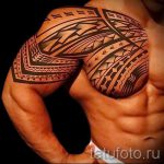 Фото тату: детализированная татуировка в стиле маори, покрывающая плечо и грудь мужчины. Черные узоры с геометрическими формами и спиралями.