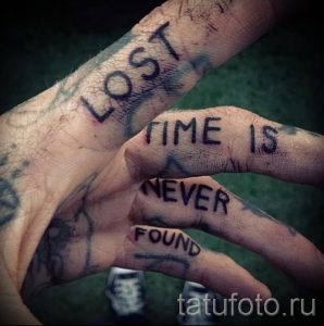 Фото тату на руках: надписи 'LOST TIME IS NEVER FOUND', выполненные в небрежном стиле. Черно-белые татуировки, имитирующие рукописный текст.