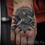 Фото тату на руке: две ласточки в стиле олд скул, с цветами и лучами солнца. Черно-белый рисунок татуировки, выполненный в традиционной технике.