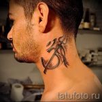 Фото татуировки на шее мужчины: стилизованное изображение символа 'Ом' с добавлением декоративных элементов.