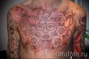Фото тату в стиле чикано на груди и плечах мужчины. Рисунок включает в себя портрет девушки, микрофон, розы и надписи.