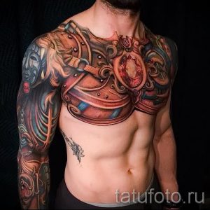 Фото тату: реалистичная татуировка на торсе мужчины в стиле биомеханика, с использованием ярких цветов и сложных механических элементов.
