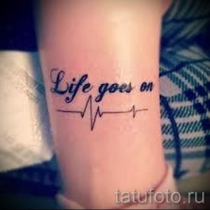 Фото тату на запястье: черная надпись 'Life goes on' с пульсирующей линией. Небольшой и минималистичный рисунок татуировки.