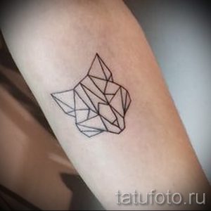 Фото минималистичной татуировки лисы, выполненной тонкими черными линиями. Геометрический стиль, лаконичный дизайн.