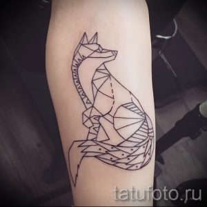 Фото тату лисы, выполненной в технике контурной татуировки черными линиями, расположенной на женской руке. Простой и элегантный рисунок татуировки.