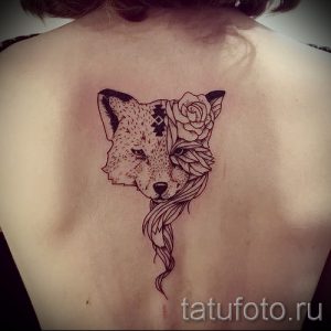 Фото тату на спине с изображением двух половинок лисы, одна из которых украшена розами и геометрическими узорами. Рисунок татуировки выполнен в черно-белой гамме.