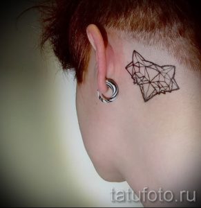 Фото тату лисы, выполненной в геометрическом стиле и расположенной за ухом. Необычное и стильное решение для тех, кто хочет выделиться.