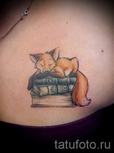 Фото тату лисы, мирно спящей на стопке книг. Нежные цвета и детальная проработка делают этот рисунок особенно привлекательным.