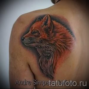Фото тату реалистичной головы лисы на плече, выполненное в теплых коричневых и серых тонах. Детализированный рисунок татуировки с акцентом на шерсть и глаза лисы.