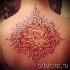 Фото тату: красивый рисунок лотоса в стиле мандала на женской спине, выполненный в нежных розовых тонах с тонкими линиями.