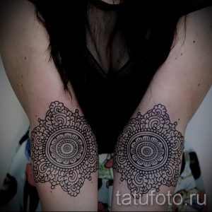 Фото тату: две одинаковые мандалы на локтях девушки. Четкие линии и геометрические узоры создают эффектный визуальный образ.