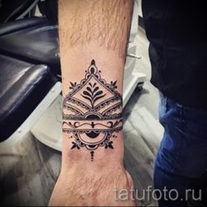 Фотография татуировки, имитирующей рисунок хной на запястье. Рисунок выполнен в черных и коричневых тонах.
