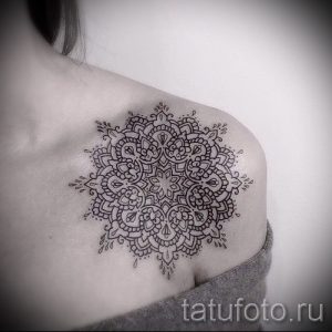 Фотография большой татуировки мандалы на плече и груди девушки. Рисунок выполнен в технике графики.