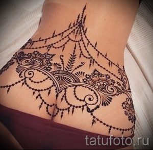 Фото татуировки хной на женской спине и ягодицах. Сложный узор с использованием растительных мотивов и геометрических фигур.