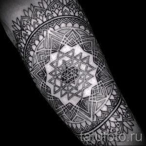 Фото тату: сложная мандала, выполненная в технике дотворк, покрывает всю поверхность предплечья. Черно-белый рисунок татуировки с высокой детализацией.