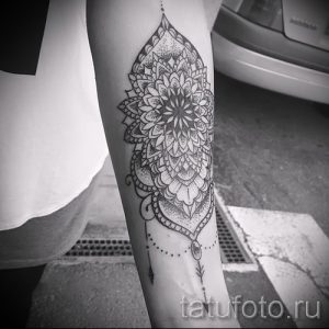 Черно-белое фото татуировки мандалы на женском предплечье. Детализированный рисунок с тонкими линиями и точками.