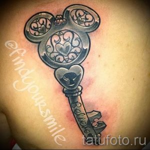 Фото тату ключа, головка которого выполнена в форме головы Микки Мауса. На стержне ключа надпись 'Believe'. Рисунок татуировки выполнен в черно-серых тонах.