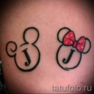 Фото парной татуировки с головами Микки и Минни Маус, внутри которых написаны инициалы 'J'. Рисунок татуировки выполнен в черном цвете с красным бантиком у Минни Маус.