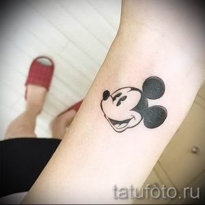Фото тату головы Микки Мауса на руке, выполненного в классическом черно-белом стиле. Простой и узнаваемый рисунок татуировки.